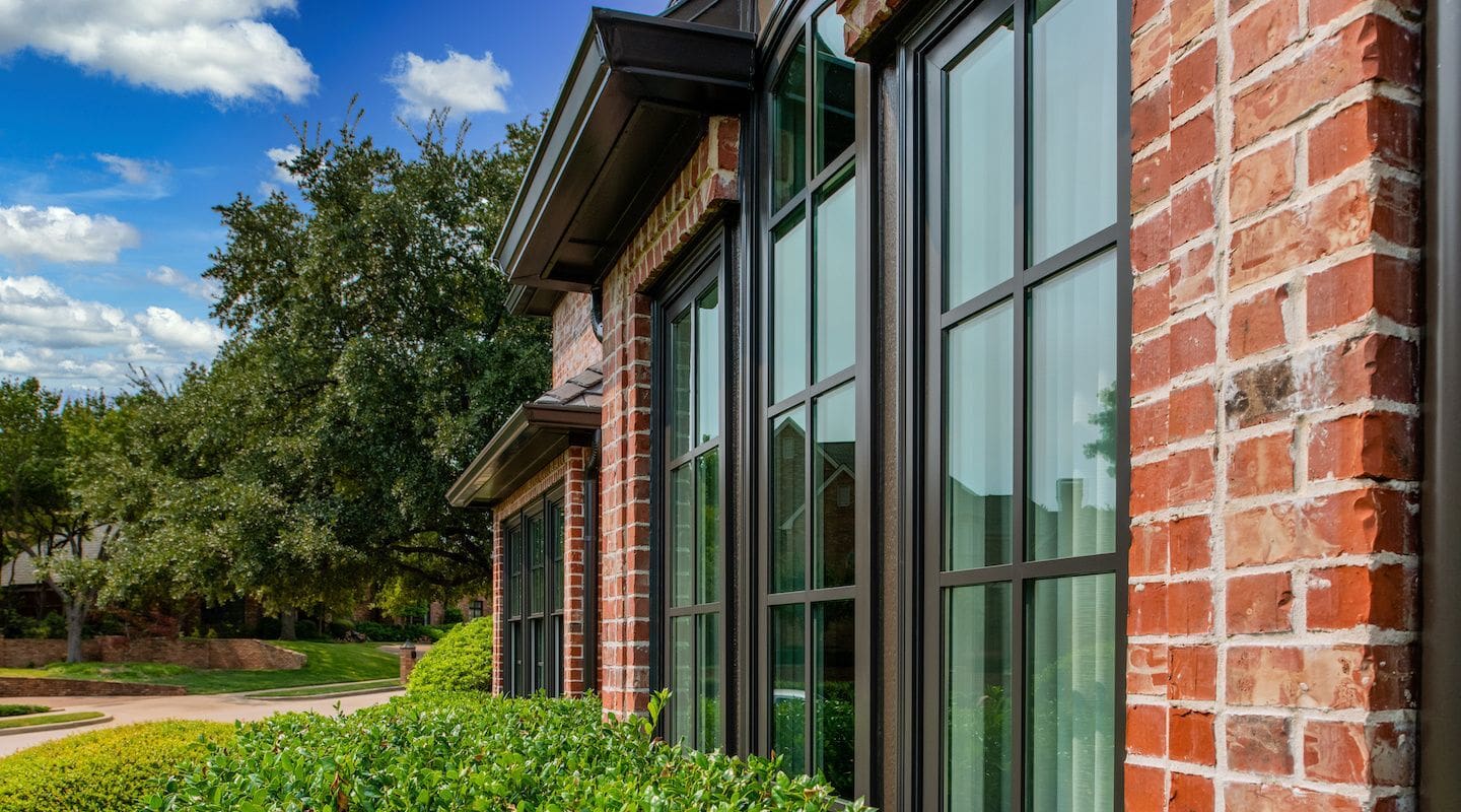 Angle view of dark-framed grid windows set in a red brick house exterior.